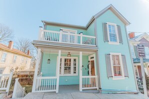 Uma casa de dois andares com varanda, alpendre e garagem.