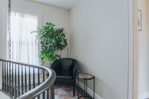 Una escalera con una silla negra y una planta en maceta en un rincón.