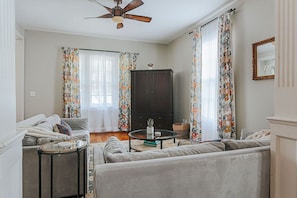 Una sala de estar con sofá, mesa de centro, mueble y ventilador de techo.