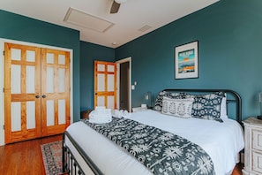 Ein Schlafzimmer mit einem Bett, einer Holztür, einem gerahmten Bild und einem Nachttisch.