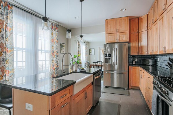 A modern kitchen with wooden cabinets, stainless steel appliances, and a black countertop.