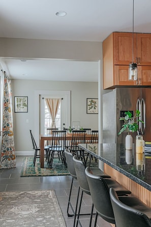 A modern kitchen with a central island, wooden cabinets, and a stainless steel refrigerator.