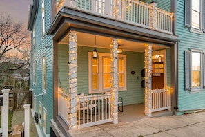 A two-story house with a porch decorated with string lights, a wooden fence, and a sign that reads 'Zondervan.'