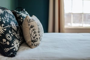 Una cama con ropa de cama blanca y almohadas decorativas con motivos florales.