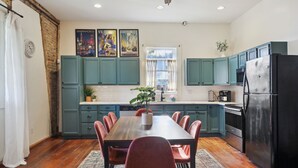 A kitchen with teal cabinets, a black refrigerator, and a dining table with red chairs.