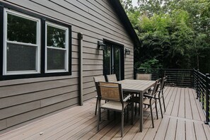 Eine Terrasse mit Tisch und Stühlen, einem Geländer und einem Gebäude mit Fenstern und Türen.