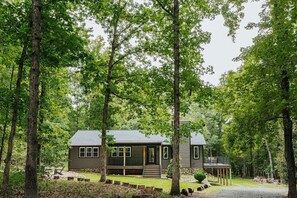 A cabin with a porch, surrounded by trees.