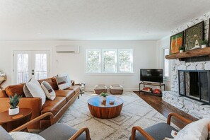 Un salon moderne avec une cheminée en pierre, un canapé en cuir marron, une table basse ronde et un téléviseur à écran plat.