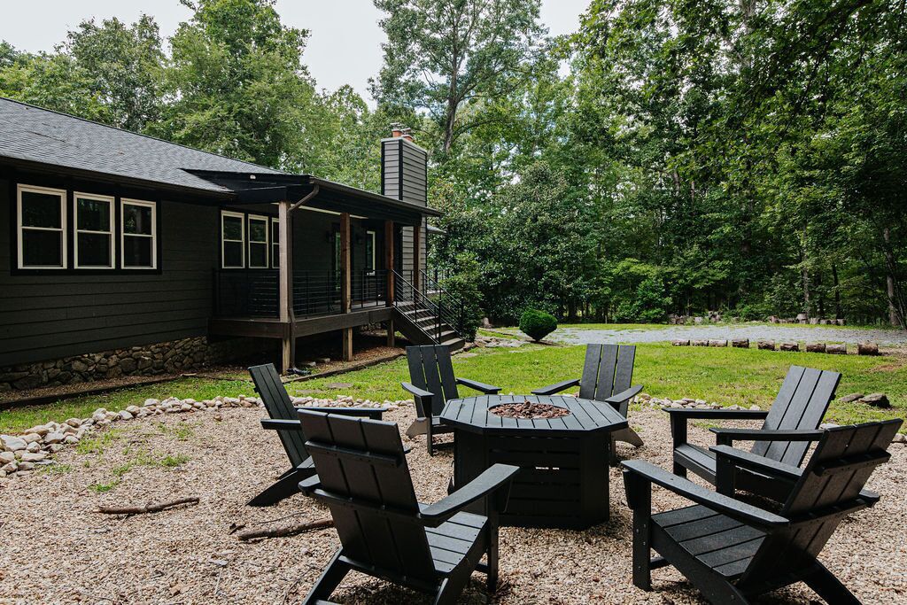 A deck with Adirondack chairs and a fire pit, surrounded by a gravel area and a wooden deck.