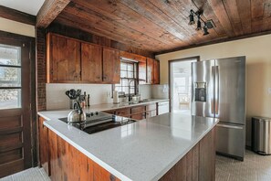 Eine Küche mit Holzausstattung, einem Edelstahlkühlschrank und einer großen Kochinsel mit Wasserkocher.