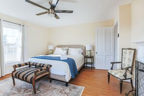 A bedroom with a bed, a chair, a desk, and a ceiling fan.
