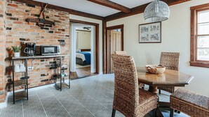 A dining area with a brick wall, wooden beams, and wicker chairs.