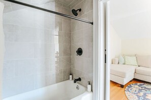 Een moderne badkamer met bad, douche en een douchecabine met glazen wanden.