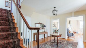 A staircase with a patterned carpet, a wooden railing, and a chandelier.