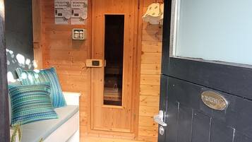 Une cabane en bois avec un sauna, un banc doté de coussins et un plancher carrelé.