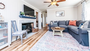A living room with a fireplace, a sofa set, a coffee table, and a ceiling fan. - 3 Queen Beds, 2 min to Fairgrounds, Fenced Yard (Perry)