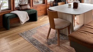 A cozy cabin interior with a wooden ceiling, large windows, a dining area with a table and chairs, and a bench with a blanket. - Greatwood (Turtle Lake)