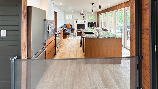 A modern kitchen with a central island, wooden flooring, and large windows. - Greatwood (Turtle Lake)