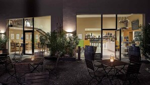 An outdoor seating area with tables and chairs, surrounded by potted plants.