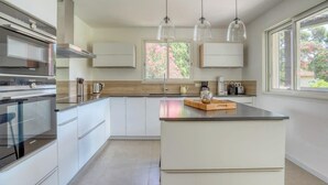 A modern kitchen with a central island, stainless steel appliances, and pendant lighting. - Designer house with swimming pool, 6 people, 300 m from the center (Le Lavandou)