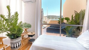 Un balcón con una cama, una mesita y una planta en maceta.