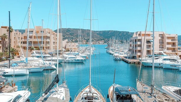 Un puerto deportivo con numerosas embarcaciones amarradas, rodeado de edificios con balcones.