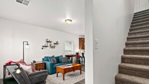 A modern living room with a grey sofa, a wooden coffee table, and a patterned rug.
