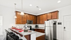 A modern kitchen with wooden cabinets, stainless steel appliances, and a granite countertop.