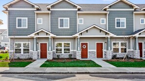 A row of townhouses with grey siding, stone accents, and a central driveway.