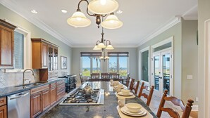 A spacious kitchen with a long island, wooden cabinets, and a central island stove. - STUNNING Oceanfront Home! Golf & Ocean Views, Hot Tub, Golf Cart, Pool Access! (Isle Of Palms)