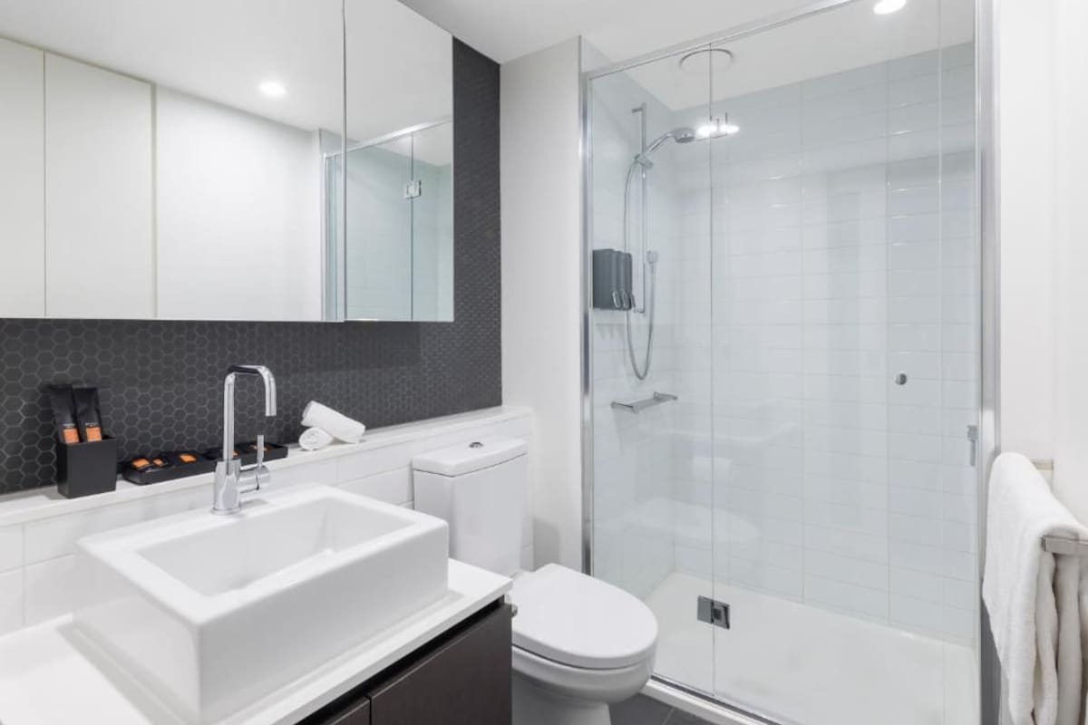 A modern bathroom with a white sink, toilet, and glass-enclosed shower.