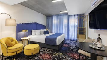 Una habitación de hotel con cama, escritorio, silla, lámpara y televisión.