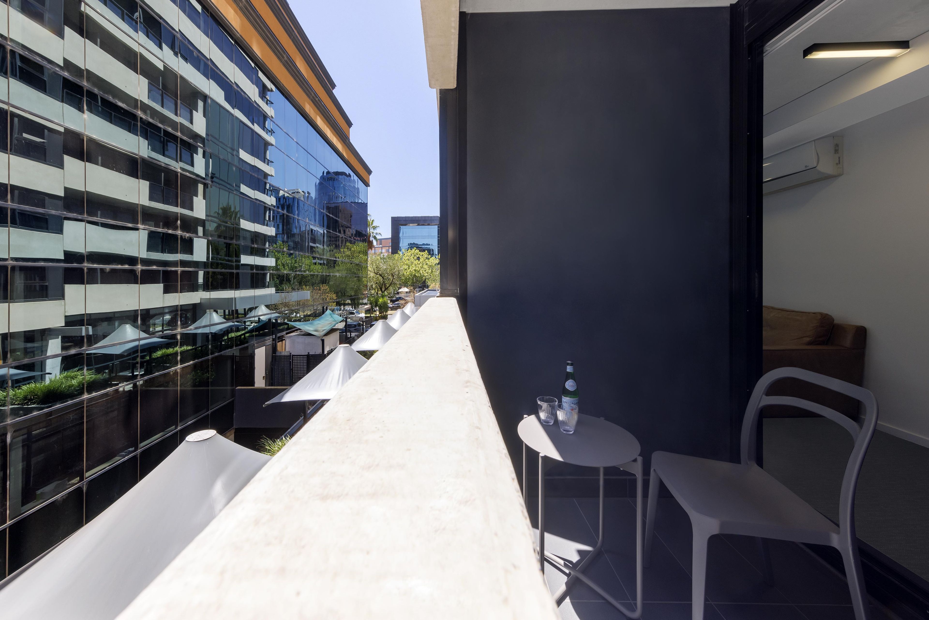 A modern outdoor seating area with a table and chairs, a bottle, and a glass.