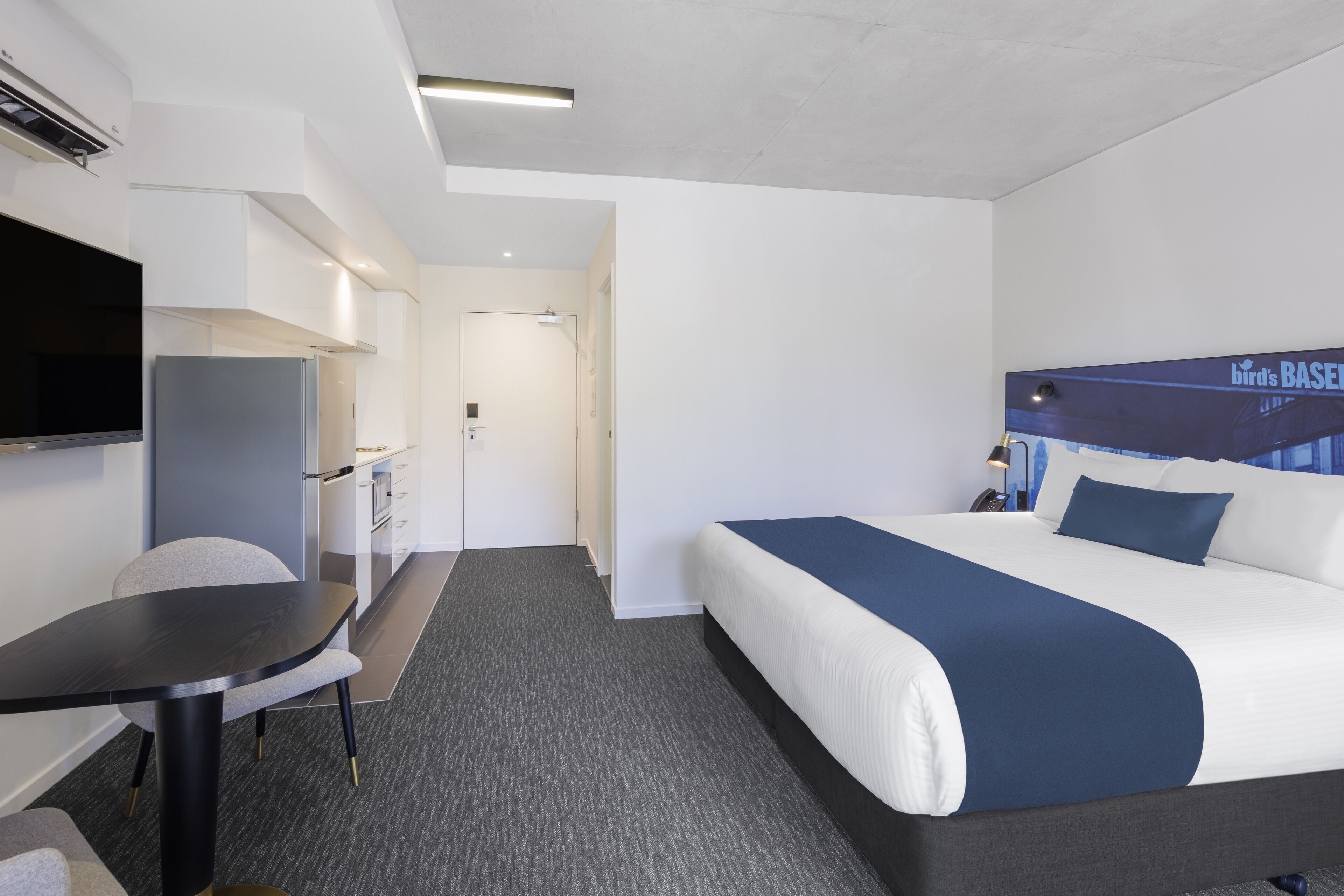 Moderni hotellihuone, jossa on sänky, työpöytä ja televisio.
