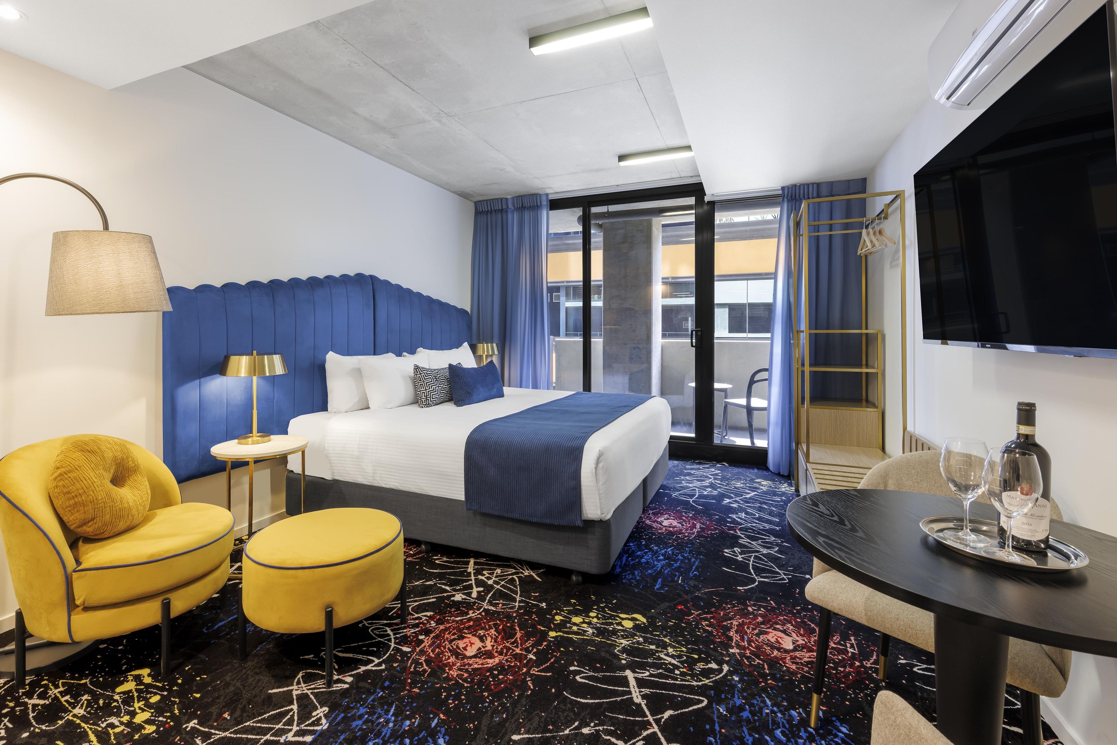Ein Hotelzimmer mit Bett, Schreibtisch, Stuhl, Fernseher und Fenster.