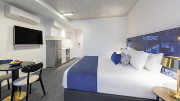 Habitación de hotel con cama, escritorio, silla, televisor, refrigerador pequeño y microondas.