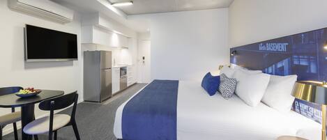 Habitación de hotel con cama, escritorio, silla, televisor, refrigerador pequeño y microondas.