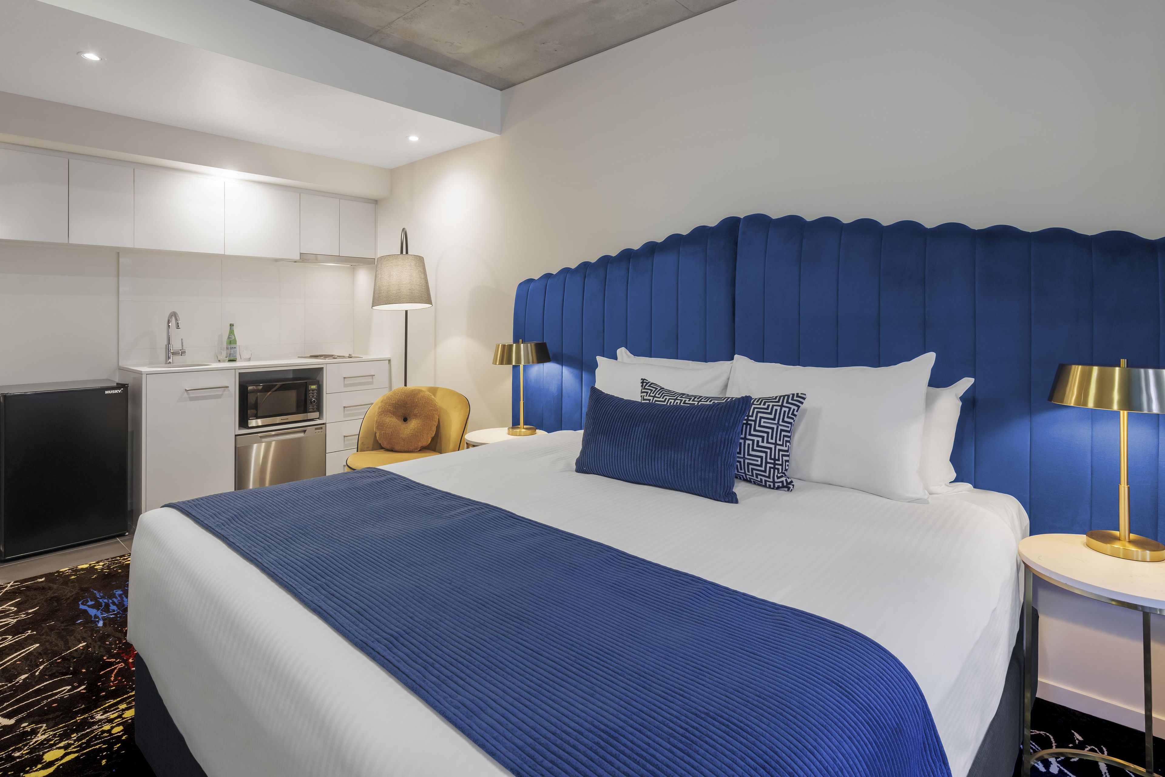 Una habitación de hotel con una cama grande, un escritorio integrado, un microondas y un refrigerador.