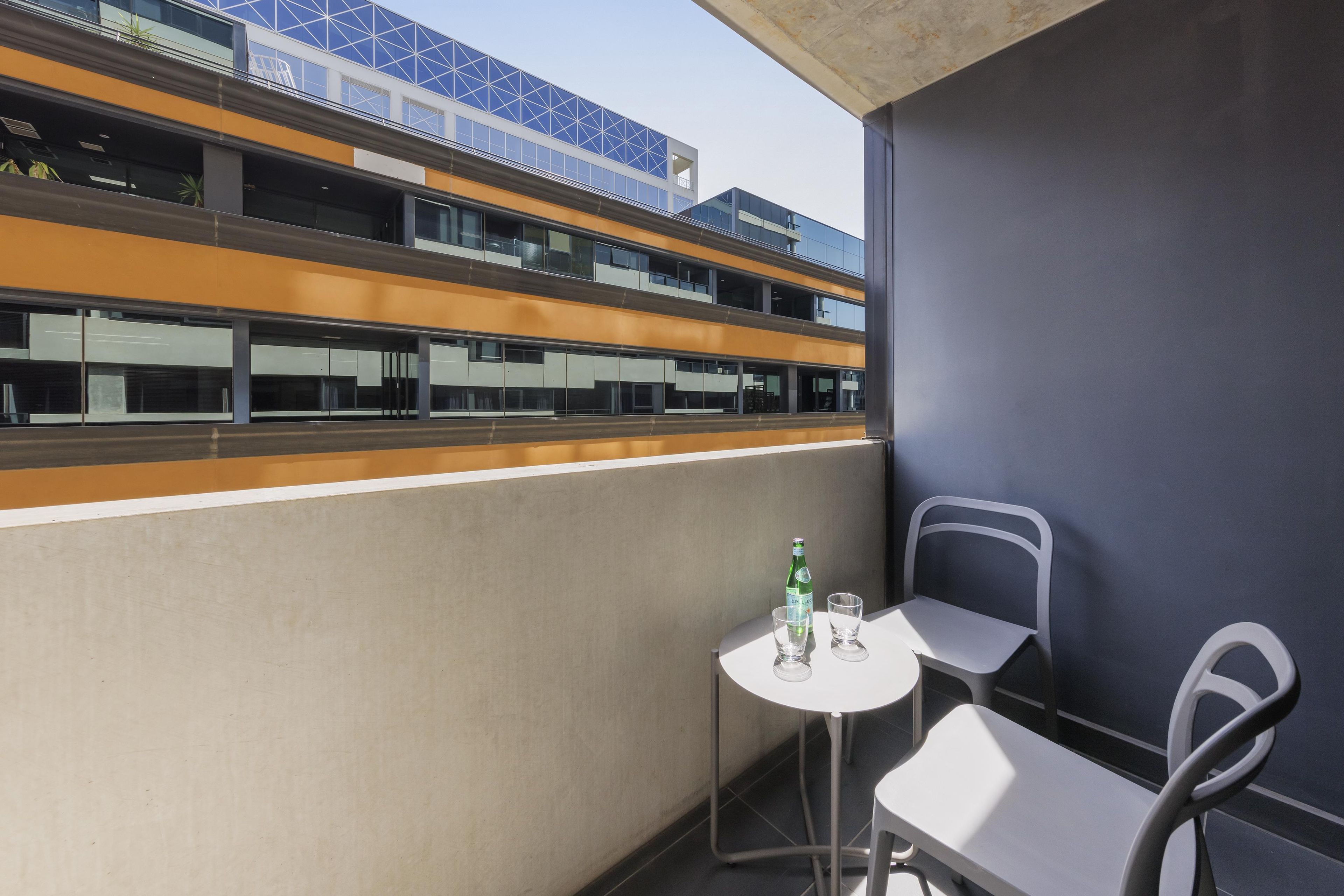 A balcony with a table and chairs, a bottle of water, and a glass.