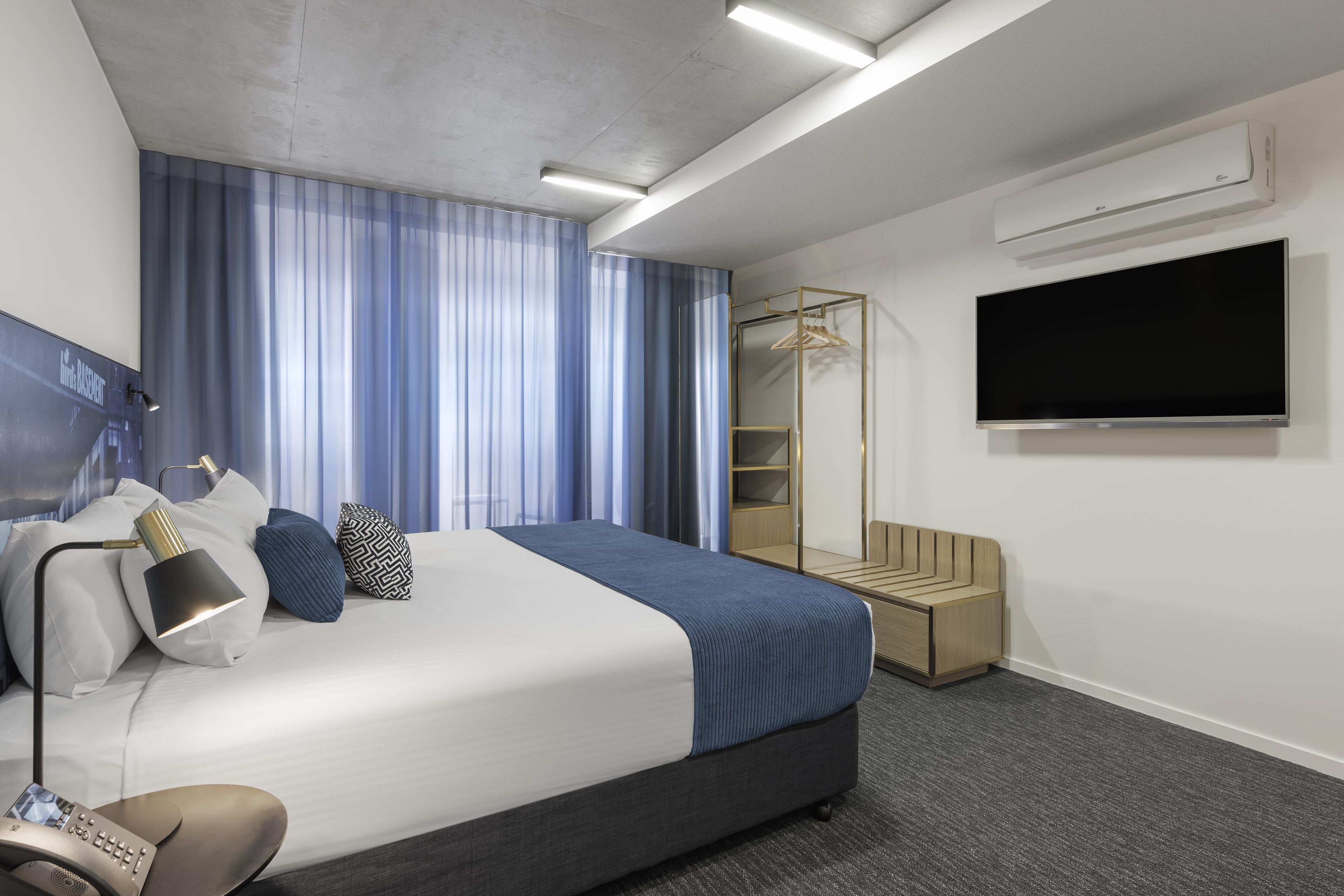 Ein Hotelzimmer mit Bett, Fernseher, Kleiderschrank und Duschbereich.