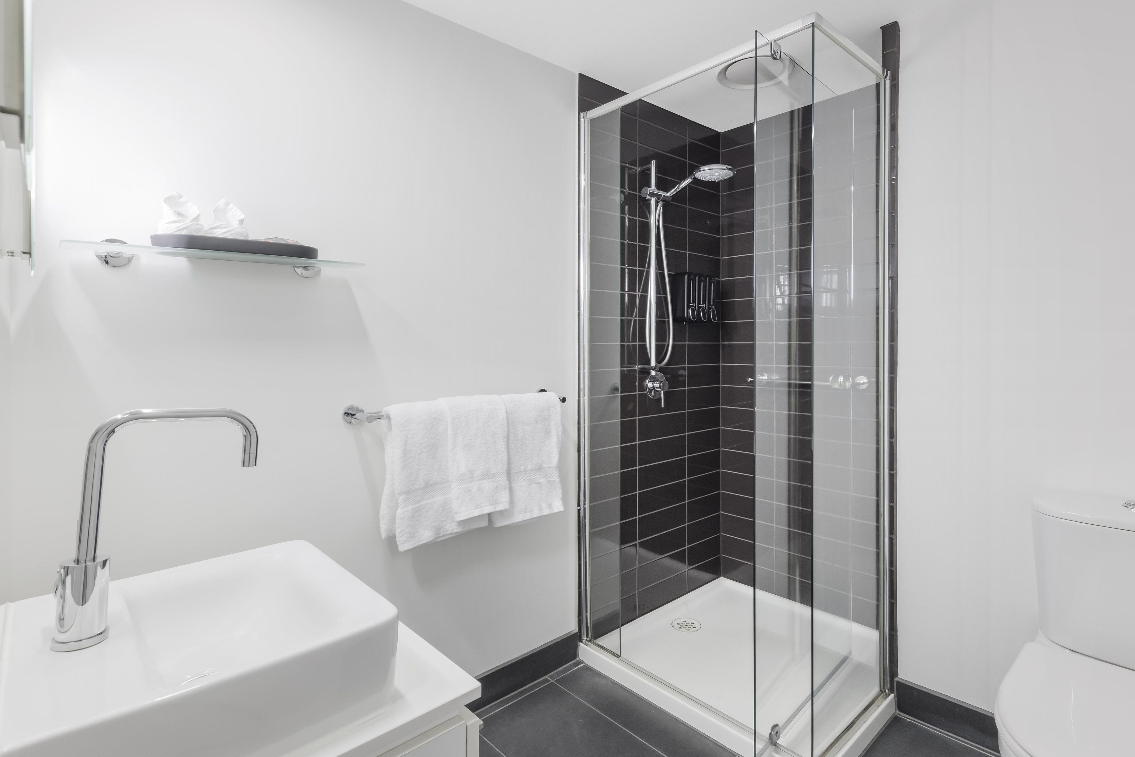 A modern bathroom with a glass-enclosed shower, a white sink, and a toilet.
