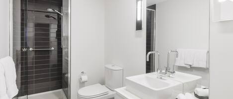 Un bagno moderno con doccia vetrata, un water e un mobile lavabo con lavandino e specchio.