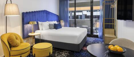 Una habitación de hotel con cama, escritorio, silla, lámpara y televisión.