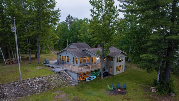 A two-story cabin with a deck, surrounded by trees. - Lakefront Getaway Near Munising & Trails- Sleeps 10 (Manistique)