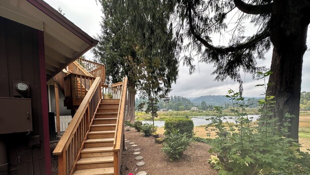 A wooden staircase leading to a house with a view of a lake and hills in the background. - The Lewis River Salmon Shores - Waterfront View & Fishing,  Book It Now! (Woodland)