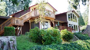 A two-story lodge with a wooden staircase, a balcony, and a large window. - The Lewis River Salmon Shores - Waterfront View & Fishing,  Book It Now! (Woodland)