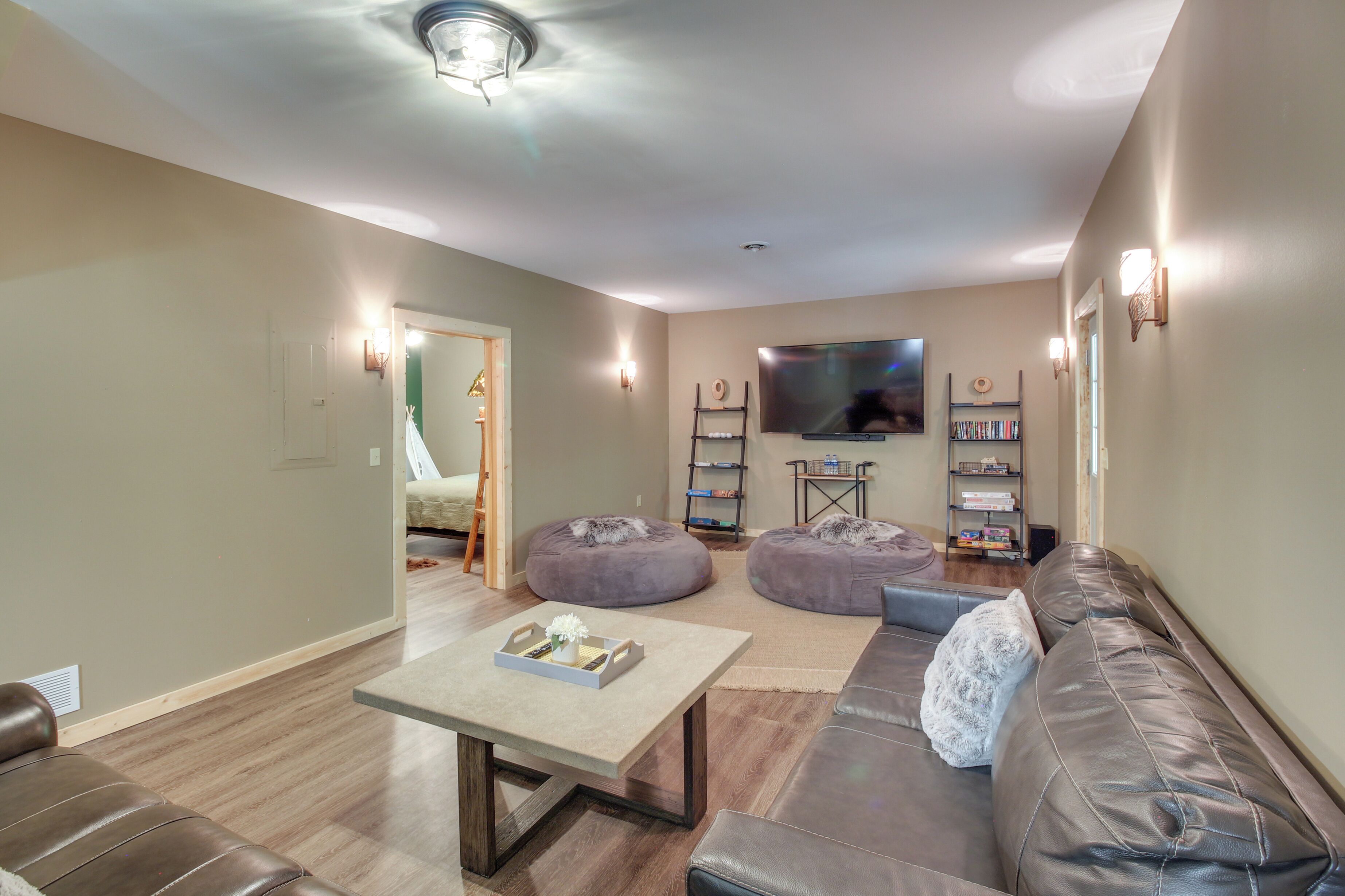 A living room with a sofa, two bean bags, a coffee table, a TV, and a bookshelf.