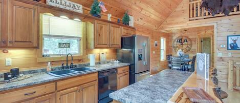 A wooden cabin kitchen with granite countertops, stainless steel appliances, and a dining area with a chandelier.