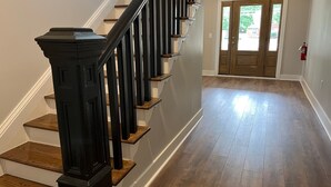 A staircase with wooden steps and black railings, leading to a door with a glass panel. - Charming 1910 Luxury Condo in Downtown Fuquay - Steps to Parks & Eateries (Fuquay-Varina)