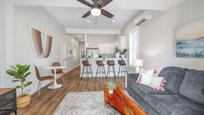 A modern living room with a grey sofa, a wooden coffee table, and a ceiling fan. - Charming 1910 Luxury Condo in Downtown Fuquay - Steps to Parks & Eateries (Fuquay-Varina)